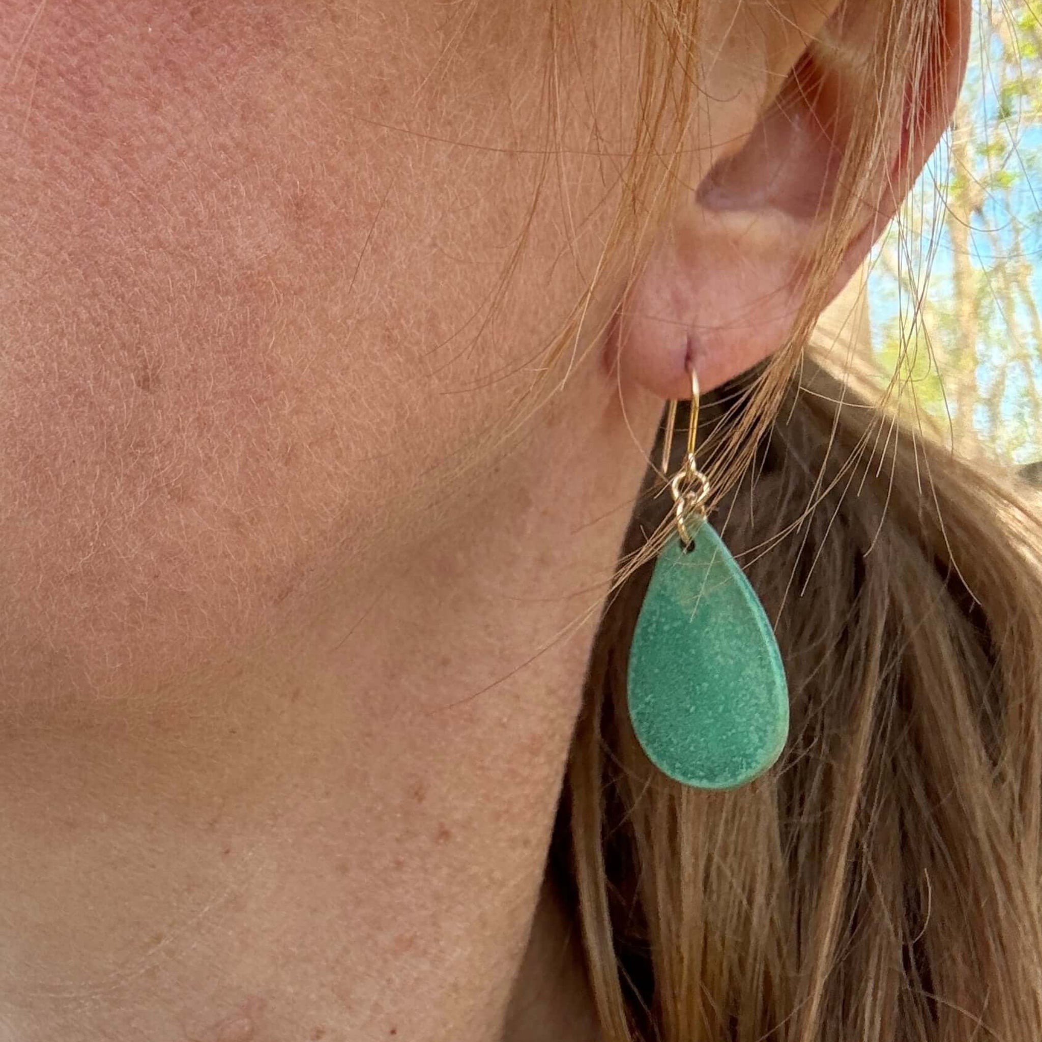 woman wearing teardrop shaped green earrings