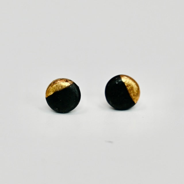 Black and gold round stud earrings on a light gray background