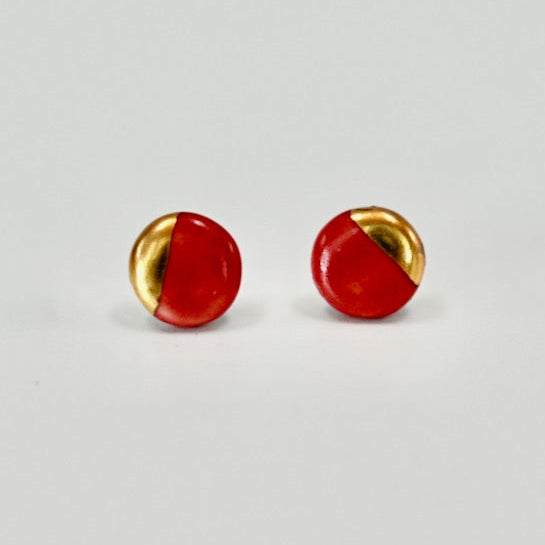 Pair of round earrings with gold and red design on a light gray background