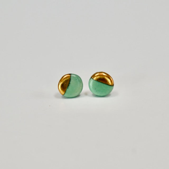 Pair of green and gold circle earrings on a light gray background