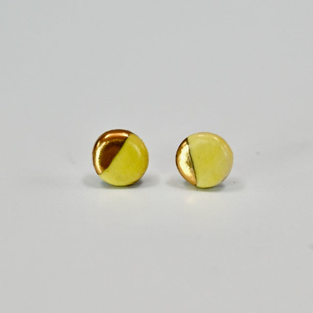 Pair of yellow and gold round circle stud earrings on a light gray background