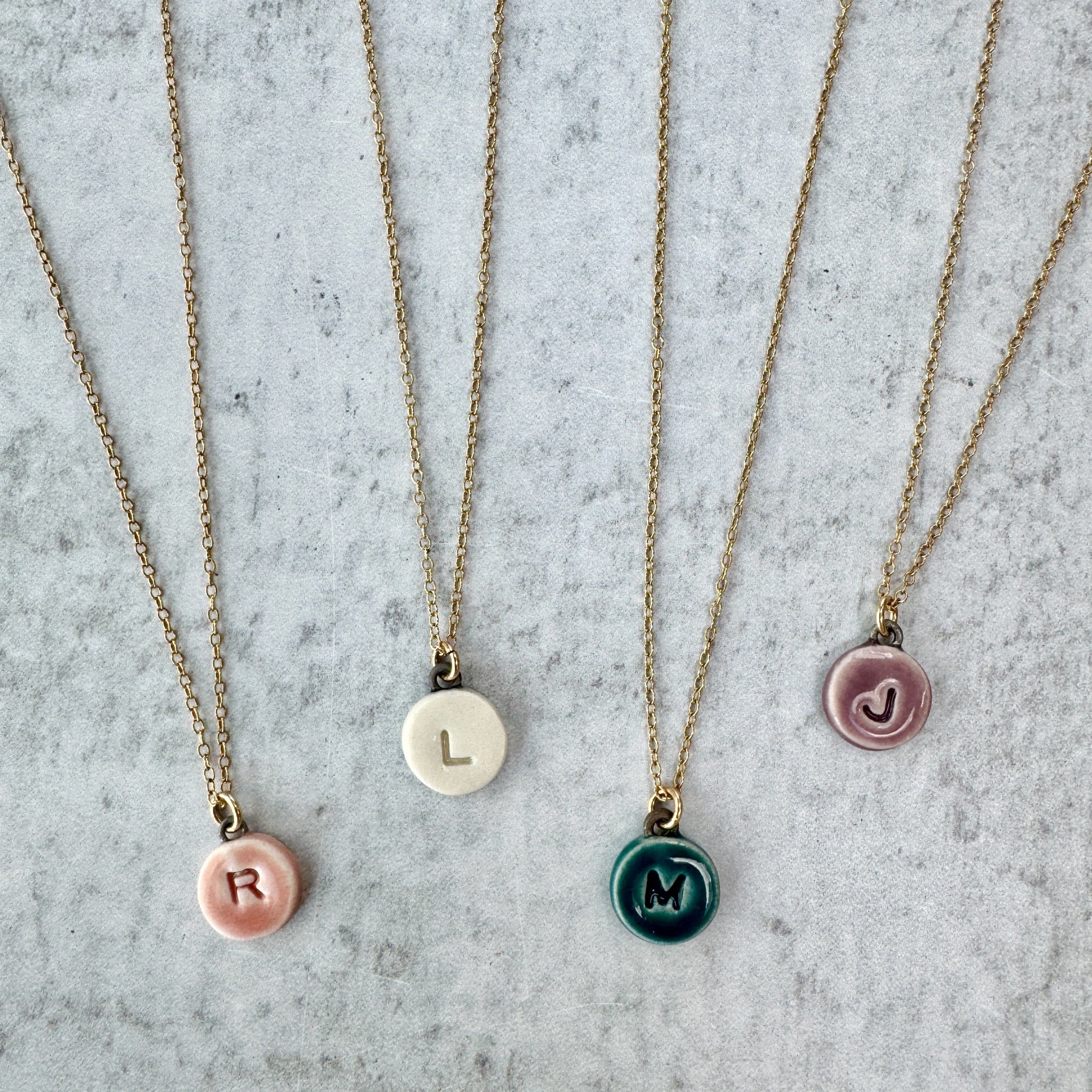 4 small circular necklaces in different colors: pink, ivory, teal, lavender