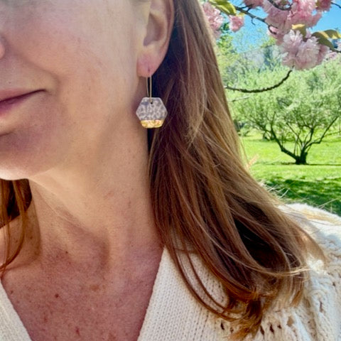woman wearing lavender and gold hexagonal shaped dangle earring