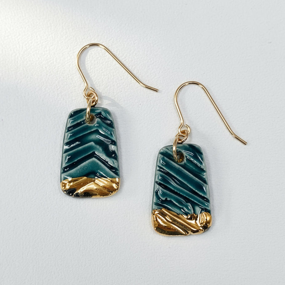 Teal and gold chevron patterned earrings on a white background