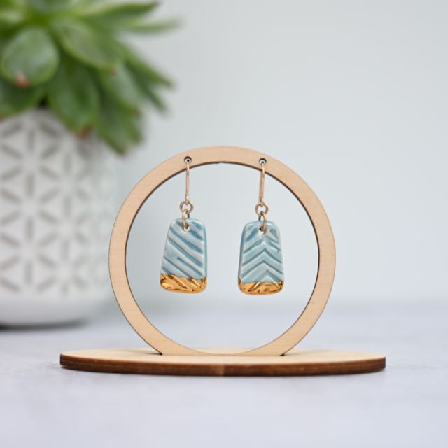 Pair of earrings on a wooden stand with a light background