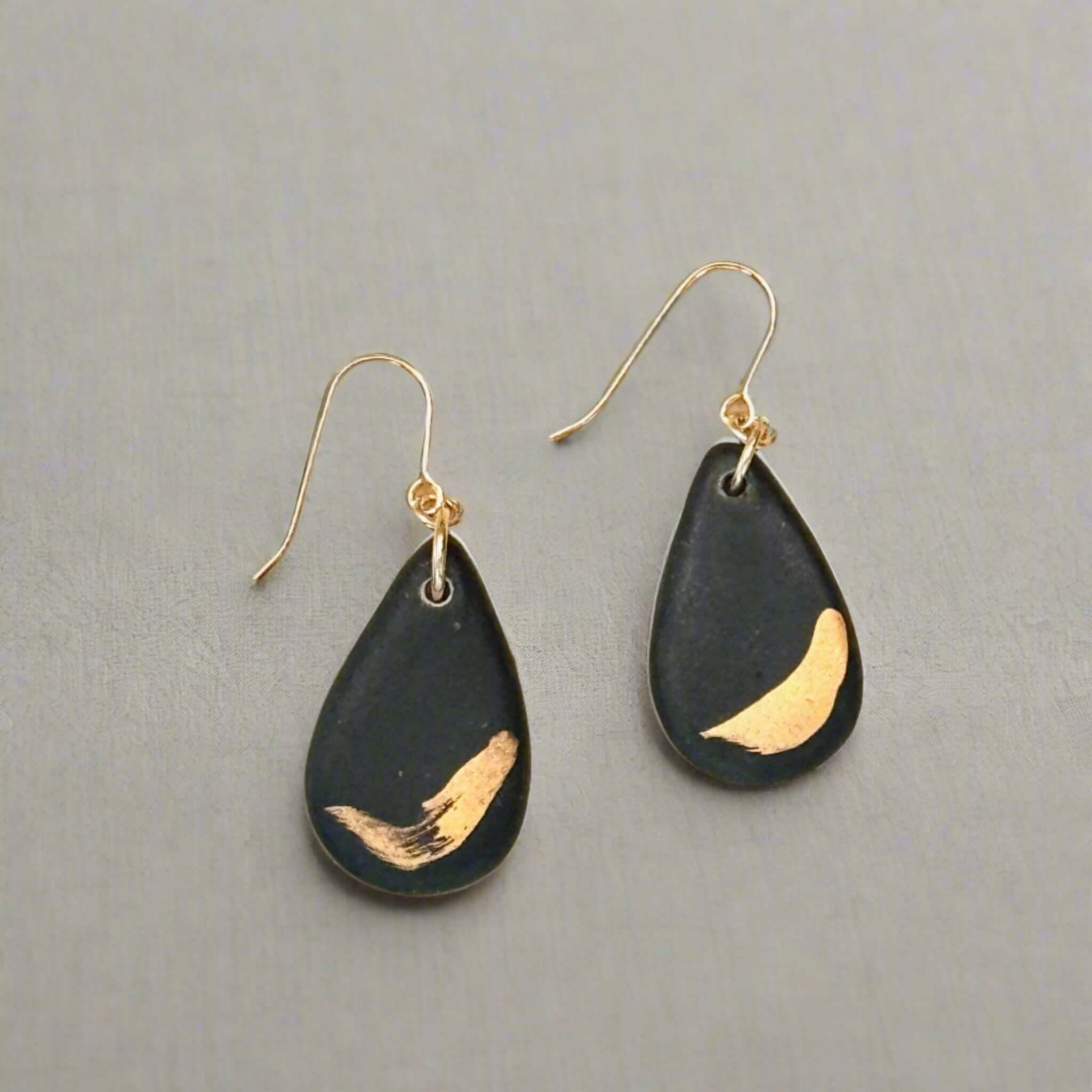 teardrop shaped black earrings with gold brushstroke detail and gold ear wires