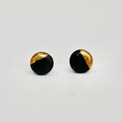 Black and gold round stud earrings on a light gray background