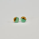 Pair of green and gold circle earrings on a light gray background