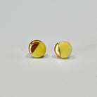 Pair of yellow and gold round circle stud earrings on a light gray background