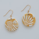 Handmade Sunprint porcelain earrings with raised floral relief, golden ochre glaze and gold-filled ear wires by Hudson Ceramics
