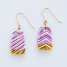 A pair of handmade porcelain earrings with gold accents and purple stripes, attached to gold-filled ear wires.