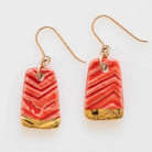 A pair of handmade porcelain earrings with gold accents and red stripes, attached to gold-filled ear wires.