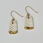 Pair of earrings with gold and beige design on a light gray background